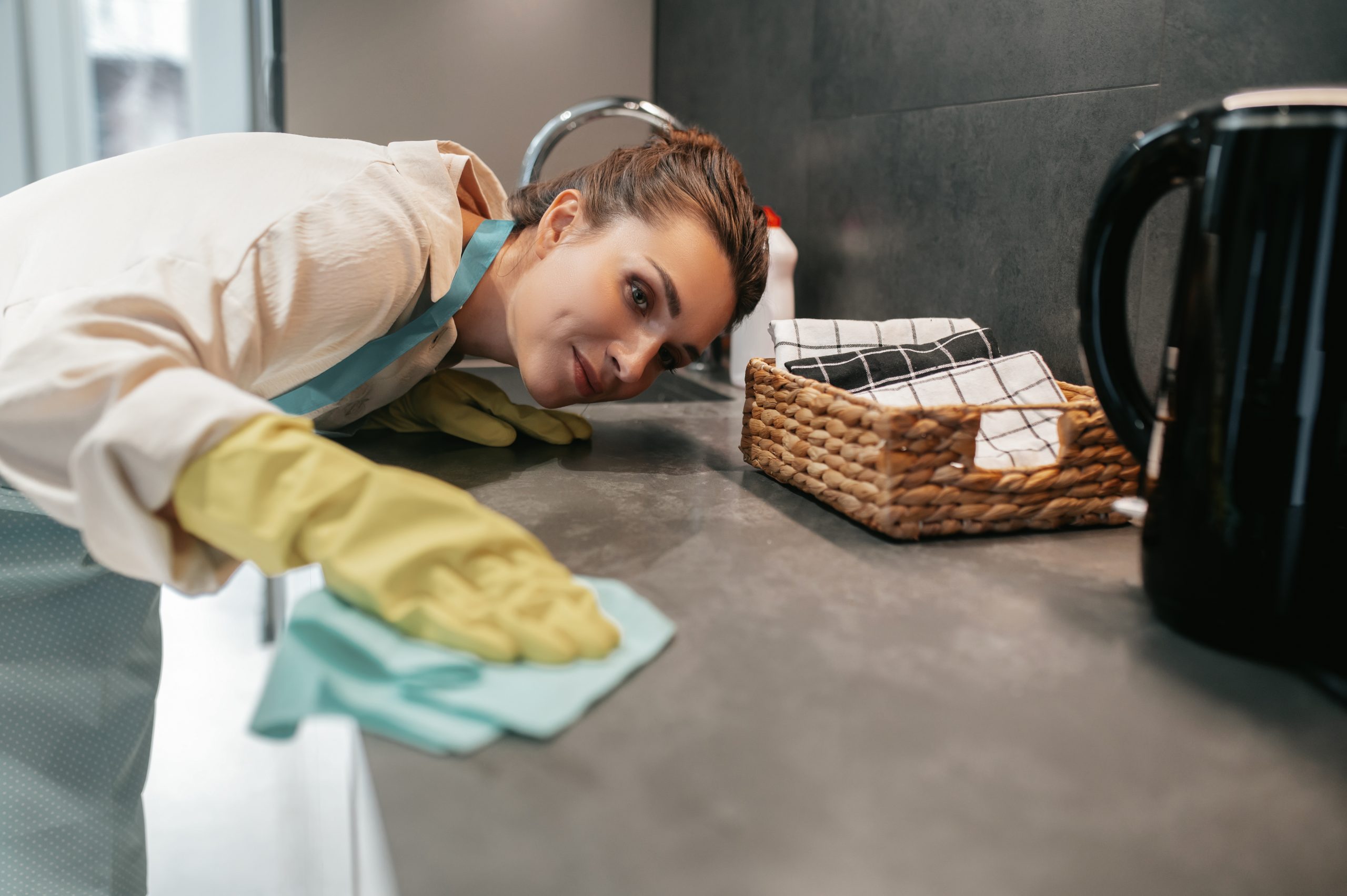 Chores. Young dark-haired woman cleaning the surfaces in the kitchen